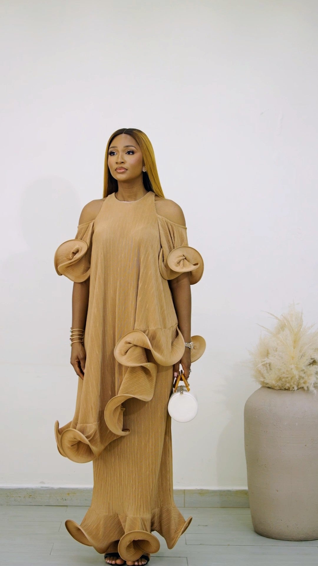 Light brown Hila Set (plisse skirt set) from Nahota Kanma, featuring cold-shoulder, ruffled sleeves, and tiered ruffles on hem.